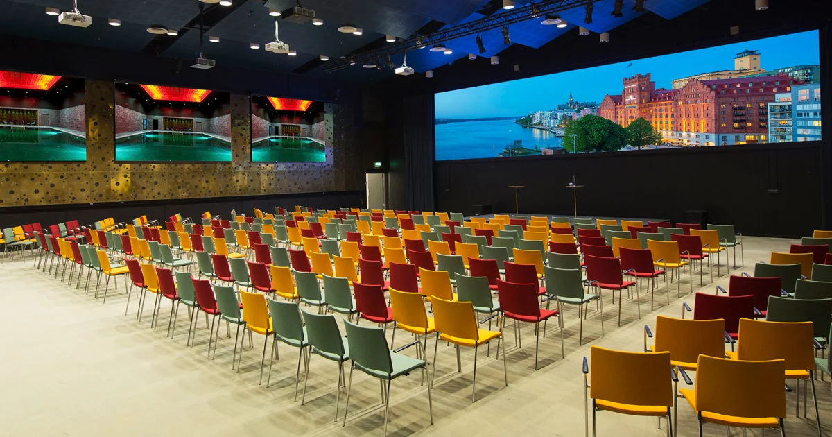 Konferenssal med färgglada stolar och stor skärm